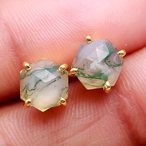 May include: A pair of gold stud earrings with green and white agate stones. The stones are faceted and have a hexagonal shape.