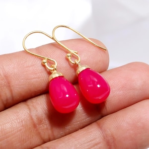 Pode incluir: Um par de brincos de argola de ouro com pedras preciosas cor de rosa em forma de lágrima.