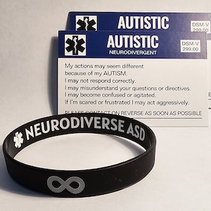 May include: Black silicone bracelet with the text "Neurodiverse ASD" and an infinity symbol. The bracelet is accompanied by two cards with the text "Autistic Neurodivergent" and "DSM-V 299.00". The cards also include a medical symbol and text explaining that the person may have different reactions due to autism.