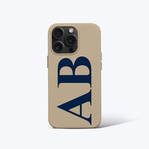 May include: A beige leather phone case with a navy blue monogram "AB" printed on the back.