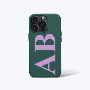 Könnte beinhalten: Eine grüne Leder-Handyhülle mit einem hellvioletten Monogramm "AB" auf der Rückseite.
