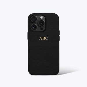 May include: Black leather phone case with a gold monogram that says "ABC".