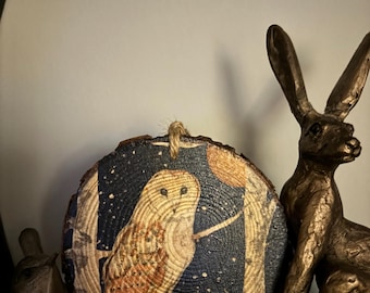 May include: A round wooden ornament with a blue and white owl illustration on a dark blue background with white stars. The owl is perched on a branch with a full moon in the background.