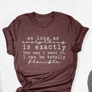 May include: A maroon t-shirt with the text "as long as everything is exactly the way I want it. I can be totally flexible" printed in white.