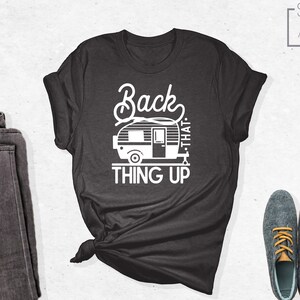 Może przedstawiać: Szary t-shirt z białym nadrukiem przedstawiającym przyczepę kempingową i tekstem "Back that thing up".