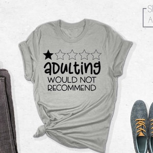 May include: A gray t-shirt with a one-star rating and the text "Adulting Would Not Recommend".