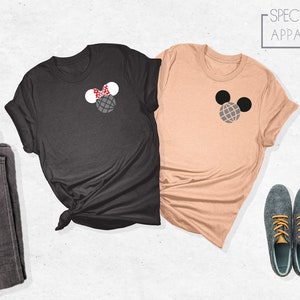 May include: Two t-shirts with a Mickey Mouse and Minnie Mouse design. The Mickey Mouse shirt is peach colored and the Minnie Mouse shirt is black. The shirts have a simple design with the character's head and ears. The text "SPECTRUM APPAREL" is in the top right corner of the image.