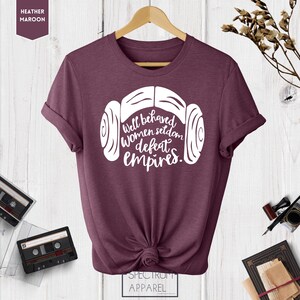 Puede incluir: Una camiseta de color marr&oacute;n jaspeado con un gr&aacute;fico blanco de los mo&ntilde;os de la princesa Leia y el texto "Well behaved women seldom defeat empires."