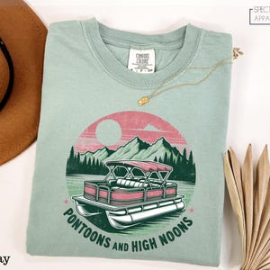 a t - shirt with a boat and mountains on it