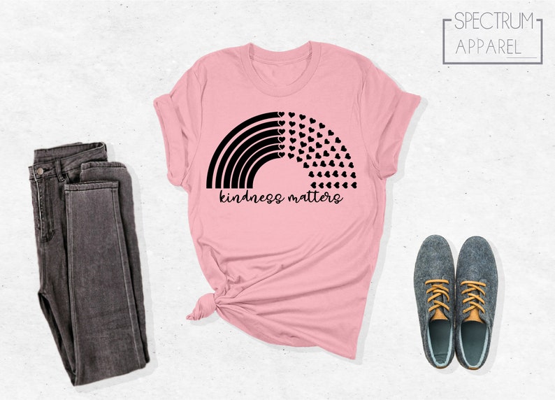 May include: Pink t-shirt with a black rainbow and hearts design. The text "kindness matters" is printed below the rainbow.