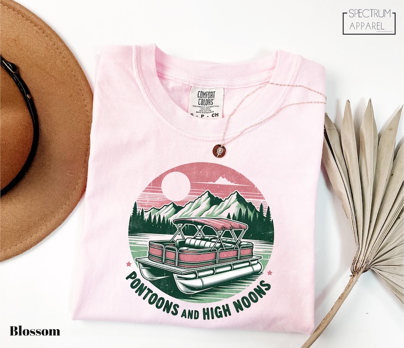 a pink shirt with a boat and mountains on it