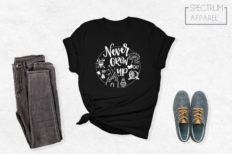 May include: Black t-shirt with white text that says "Never Grow Up" surrounded by white illustrations of Disney park icons.
