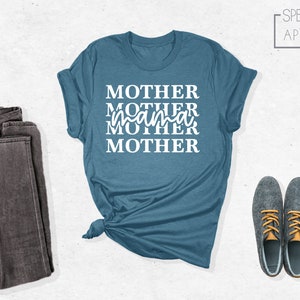 Puede incluir: Una camiseta azul turquesa con el texto "MOTHER MOTHER mama MOTHER" en letras blancas.