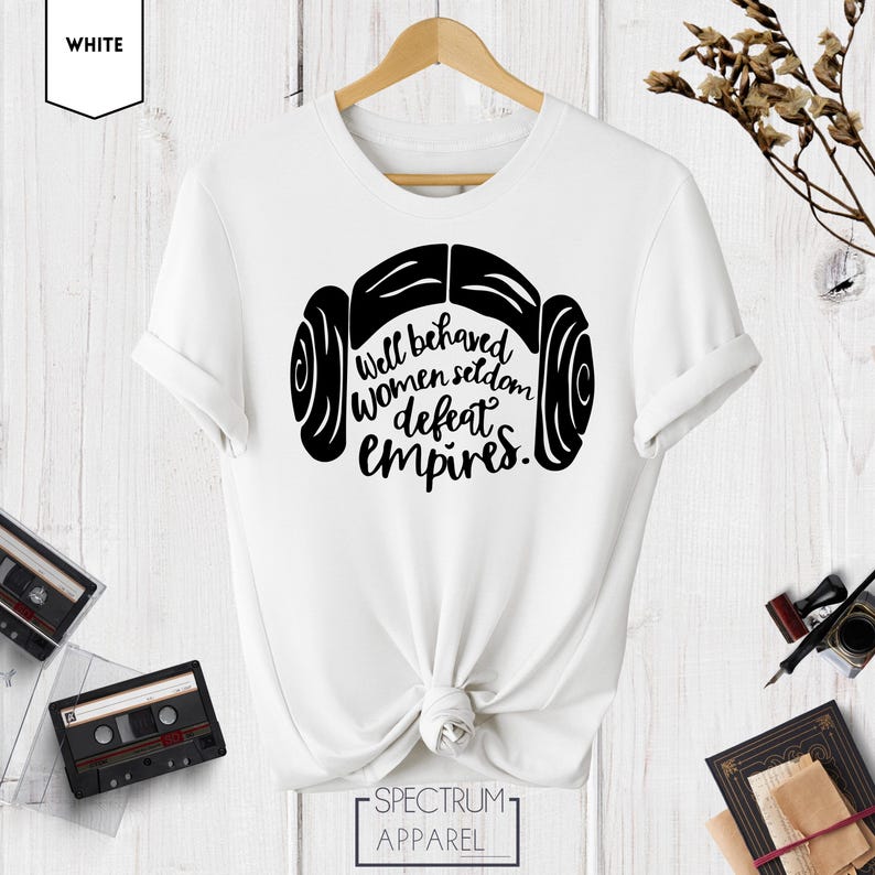 Puede incluir: Camiseta blanca con un gr&aacute;fico negro de la cabeza de una mujer con un mo&ntilde;o lateral y el texto "Well behaved women seldom defeat empires."