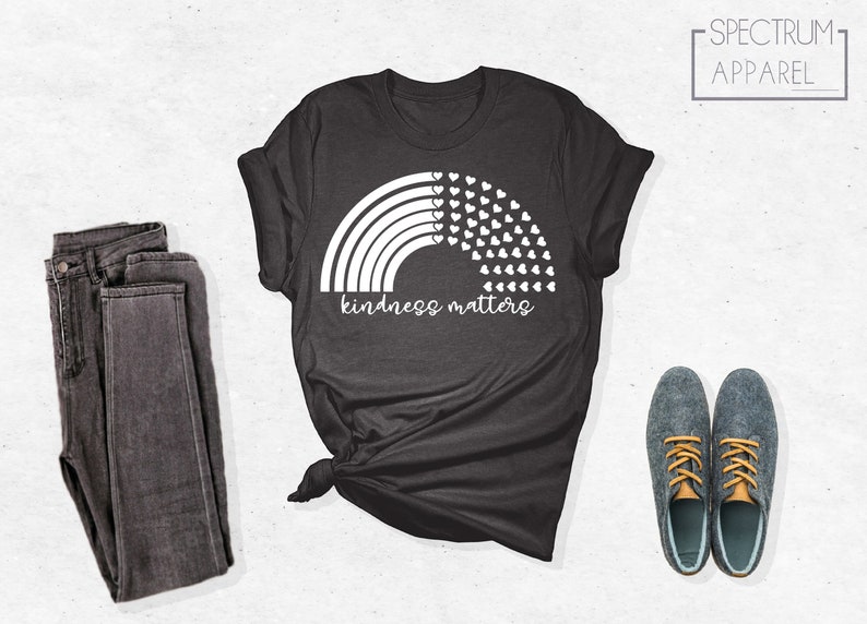 May include: A dark gray t-shirt with a white rainbow and hearts design. The text "kindness matters" is printed below the rainbow.