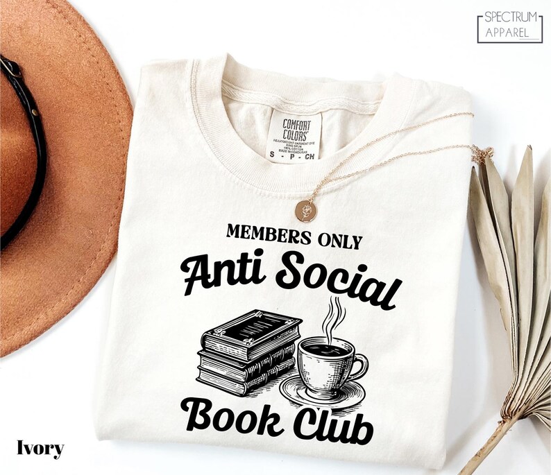 a white t-shirt with a graphic design that reads "MEMBERS ONLY Anti Social Book Club" and includes a book and a cup of coffee.