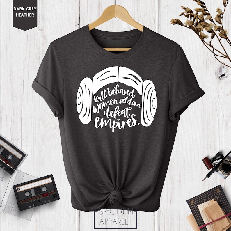 Puede incluir: Camiseta de color gris oscuro jaspeado con un gr&aacute;fico blanco de un casco de un personaje de Star Wars y el texto "Well behaved women seldom defeat empires."