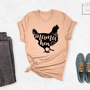 May include: A peach-colored t-shirt with a black silhouette of a chicken and the text "mama hen" in a stylized font.