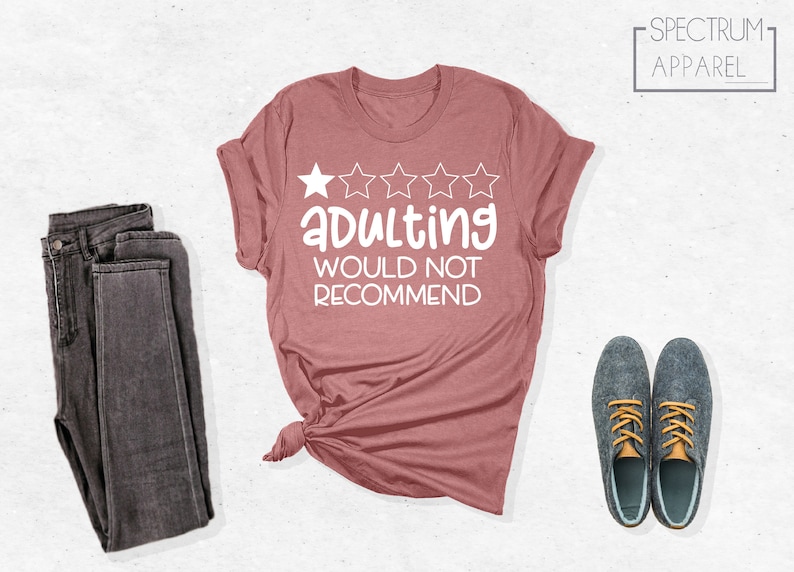 May include: A pink t-shirt with a white graphic that says "Adulting would not recommend" and has five white stars above the text.