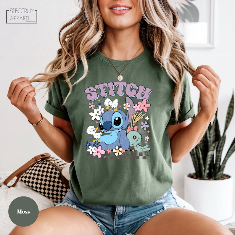 A woman wearing a green t-shirt with a colorful graphic of a cartoon character and flowers printed on it.
