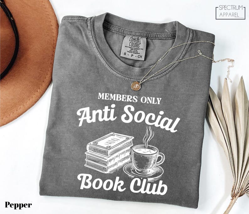 a gray t-shirt with a graphic design that reads "MEMBERS ONLY Anti Social Book Club" and includes a book and a cup of coffee.