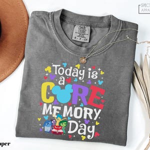 May include: Gray t-shirt with a colorful graphic that says "Today is a CORE MEMORY Day" with a Mickey Mouse head in the middle of the word "CORE". The graphic also includes characters from the movie Inside Out.