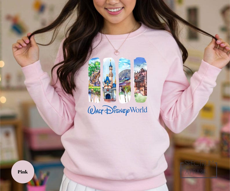A woman wearing a pink sweatshirt with a collage of Disney World images on it.