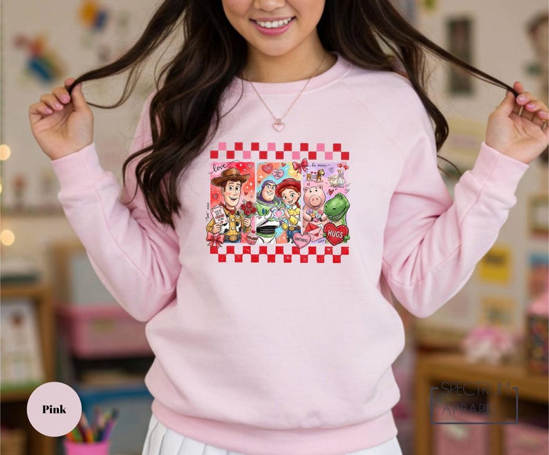 A woman wearing a pink sweatshirt with a graphic of characters from the Toy Story movie.