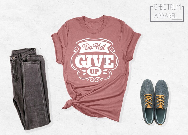 May include: A dusty rose t-shirt with a white graphic that says "Do Not Give Up" in a vintage style font.