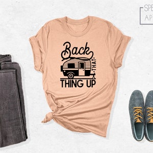 Może przedstawiać: R&oacute;żowy t-shirt z czarnym nadrukiem przedstawiającym przyczepę kempingową i tekstem "Back that thing up".