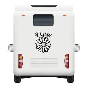 May include: A white camper van featuring a black daisy graphic and the name "Daisy" in script. The van has a rear window, taillights, and side mirrors. The tyres are black.