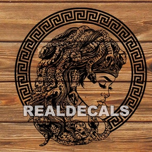 Puede incluir: Ilustración en blanco y negro de Medusa, una figura mitológica griega con serpientes por cabello, dentro de un marco circular con un patrón de clave griega. La imagen está sobre un fondo de veta de madera.