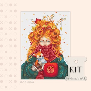 May include: Cross stitch kit featuring a girl with a crown of autumn leaves and a red scarf, holding a small fox plushie. The kit is handmade in the UK.