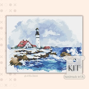 May include: A cross stitch kit depicting a lighthouse on a rocky shore with crashing waves. The lighthouse is white with a red roof and is surrounded by a small village. The sky is blue with white clouds. The kit is handmade in the UK.