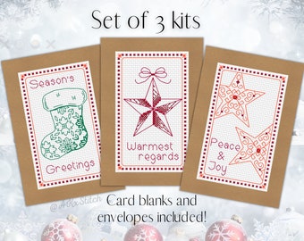 May include: Set of three Christmas cross-stitch card kits. Each kit includes a brown card blank, envelope, and floss to stitch a design. The designs are a stocking with the text "Season's Greetings", a star with the text "Warmest regards", and two stars with the text "Peace & Joy".