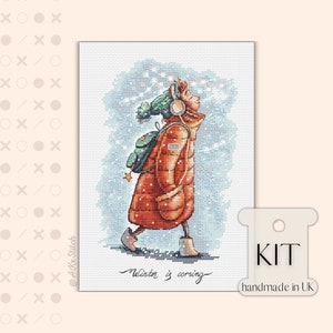 Peut inclure: Kit de point de croix repr&eacute;sentant une fille en manteau rouge et chapeau vert marchant dans la neige. Le texte "Winter is coming" est &eacute;crit sous la fille. Le kit est fait &agrave; la main au Royaume-Uni.