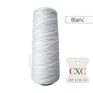 Op de afbeelding: Een spoel wit garen met het label "Blanc" en "CXC ANY LENGTH".