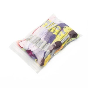 May include: A clear plastic bag filled with a variety of colorful embroidery floss. The floss is organized by color and labeled with numbers. The bag is sealed and ready to be used.