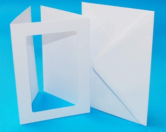 Op de afbeelding: Een witte kaart met een uitgesneden venster aan de voorkant en een witte envelop.