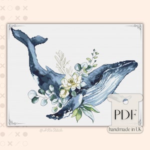 May include: Cross stitch pattern featuring a blue whale with white and green floral accents. The pattern is titled "PDF handmade in UK" and includes the social media handle "@AKxStitch".