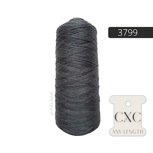 May include: A large spool of dark grey thread. The thread is tightly wound around the spool. The number "3799" is displayed on a black rectangle. A white tag with the letters "CXC" and the words "ANY LENGTH" is also visible.
