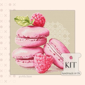 Peut inclure: Un kit de point de croix représentant une pile de macarons roses avec des framboises. Le kit est fait à la main au Royaume-Uni. L'image comprend le texte "KIT handmade in UK".