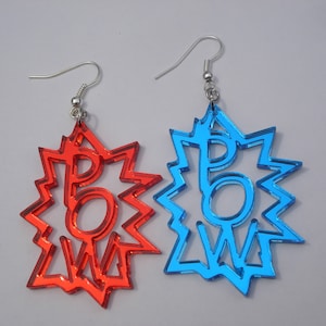 May include: A pair of earrings with a red and blue POW! design. The earrings are made of acrylic and have a silver hook.