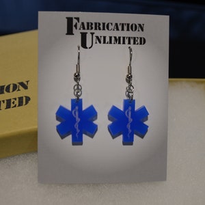 May include: A pair of blue star of life earrings with silver hooks. The earrings are on a white card with the text "Fabrication Unlimited".