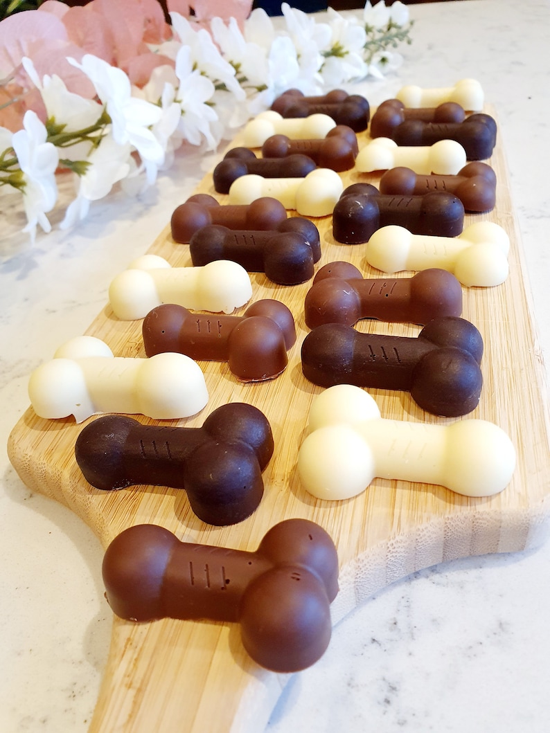May include: A wooden board with a variety of chocolate dog bone treats. The treats are in two colors: white chocolate and dark chocolate.