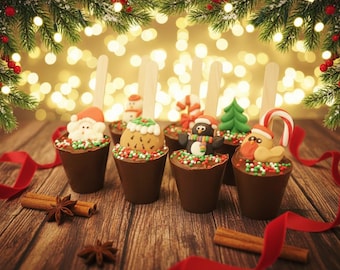 May include: A festive arrangement of chocolate cups topped with Christmas-themed decorations, including Santa, snowmen, and penguins. The cups are on a wooden surface with cinnamon sticks, star anise, and red ribbon.