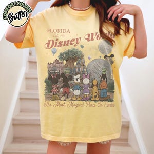 May include: Yellow t-shirt with a graphic of Disney World characters and landmarks. The shirt features the text "FLORIDA Est. 1971 Disney World" and "The Most Magical Place On Earth."