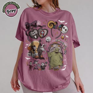 May include: Mauve t-shirt featuring a colorful graphic design with characters and elements from "The Nightmare Before Christmas." The design includes Jack Skellington, Sally, Oogie Boogie, and other iconic imagery. The shirt has the text "Comfort Colors" and "Bery" in a circle.