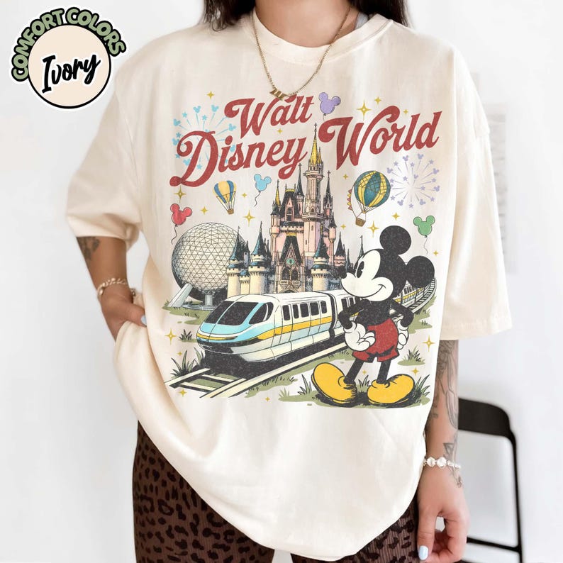 May include: Ivory t-shirt with a retro Walt Disney World design. The graphic includes the castle, monorail, Mickey Mouse, and the words "Walt Disney World". The shirt is a relaxed fit and the text is in a vintage style.