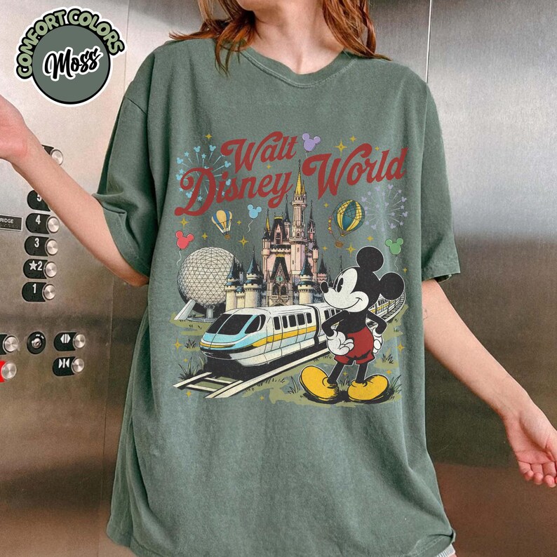 May include: Green t-shirt with a Walt Disney World graphic featuring Mickey Mouse, a monorail, Cinderella's castle, and the text "Walt Disney World". The shirt has a distressed, vintage appearance.